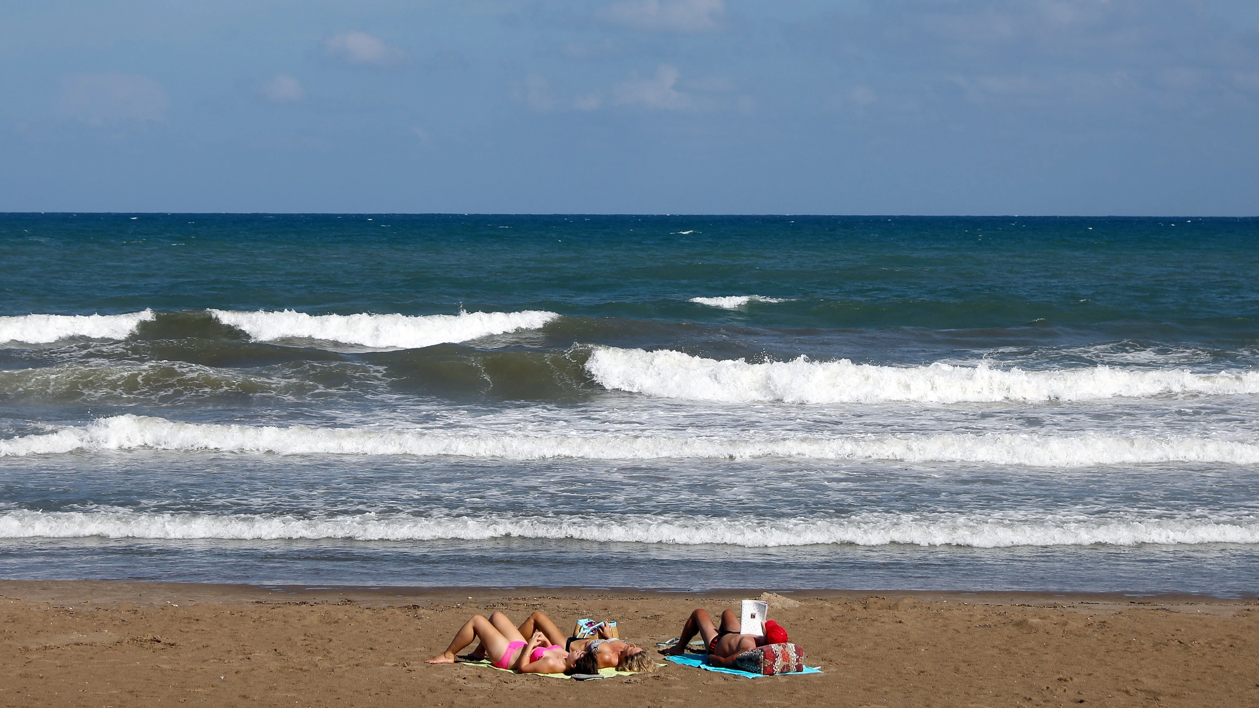 Tres personas toman el sol, el pasado mes de septiembre en la playa de la Malvarrosa de Valencia