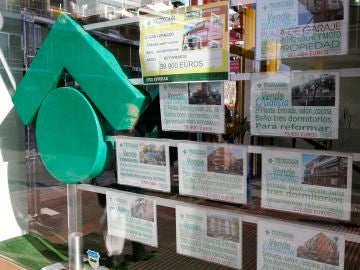 Numerosos carteles de venta de pisos ocupan el escaparate de una entidad inmobiliaria Numerosos carteles de venta de pisos ocupan el escaparate de una entidad inmobiliaria