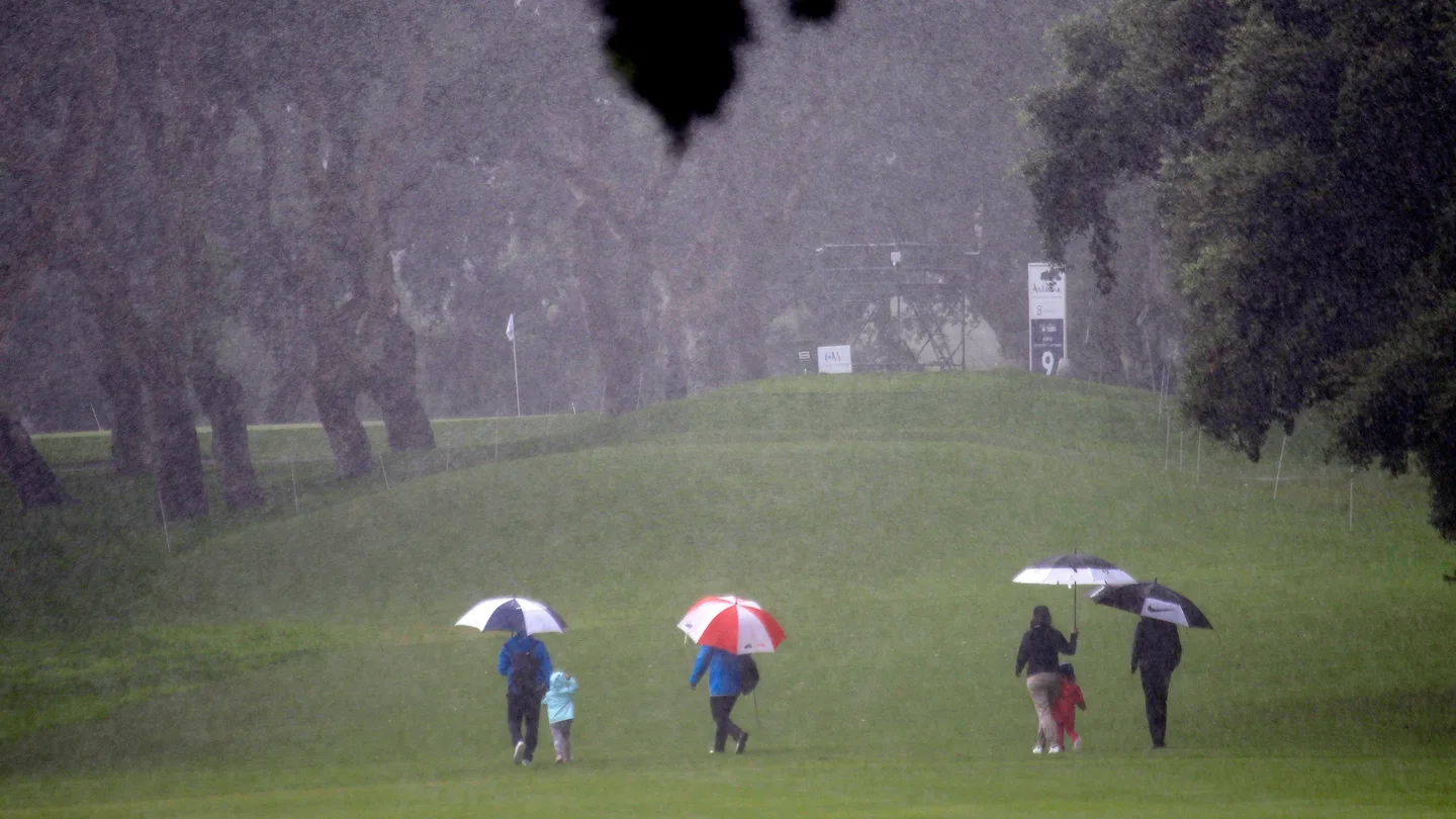 Espectadores cruzan bajo la fuerte lluvia uno de los hoyos del campo del Real Club Espectadores cruzan bajo la fuerte lluvia uno de los hoyos del campo del Real Club