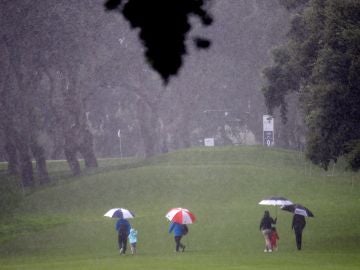 Espectadores cruzan bajo la fuerte lluvia uno de los hoyos del campo del Real Club Espectadores cruzan bajo la fuerte lluvia uno de los hoyos del campo del Real Club
