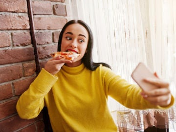 Chica grabándose en Instagram Stories mientras come una pizza