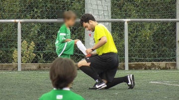 Un árbitro le ata los cordones a un niño