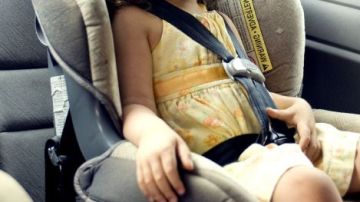 Imagen de archivo de una niña en una sillita en un coche