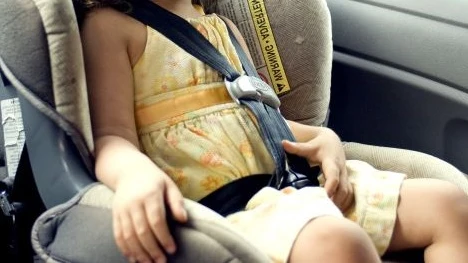 Imagen de archivo de una niña en una sillita en un coche