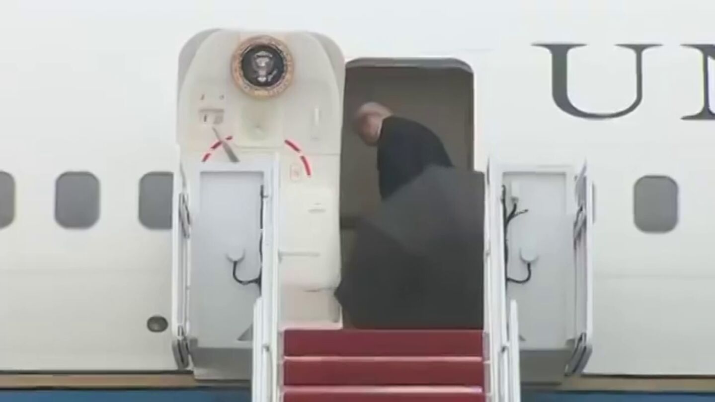 Trump tira su paraguas abierto antes de entrar en el avi&oacute;n presidencial y un agente del Servicio Secreto lo recoge