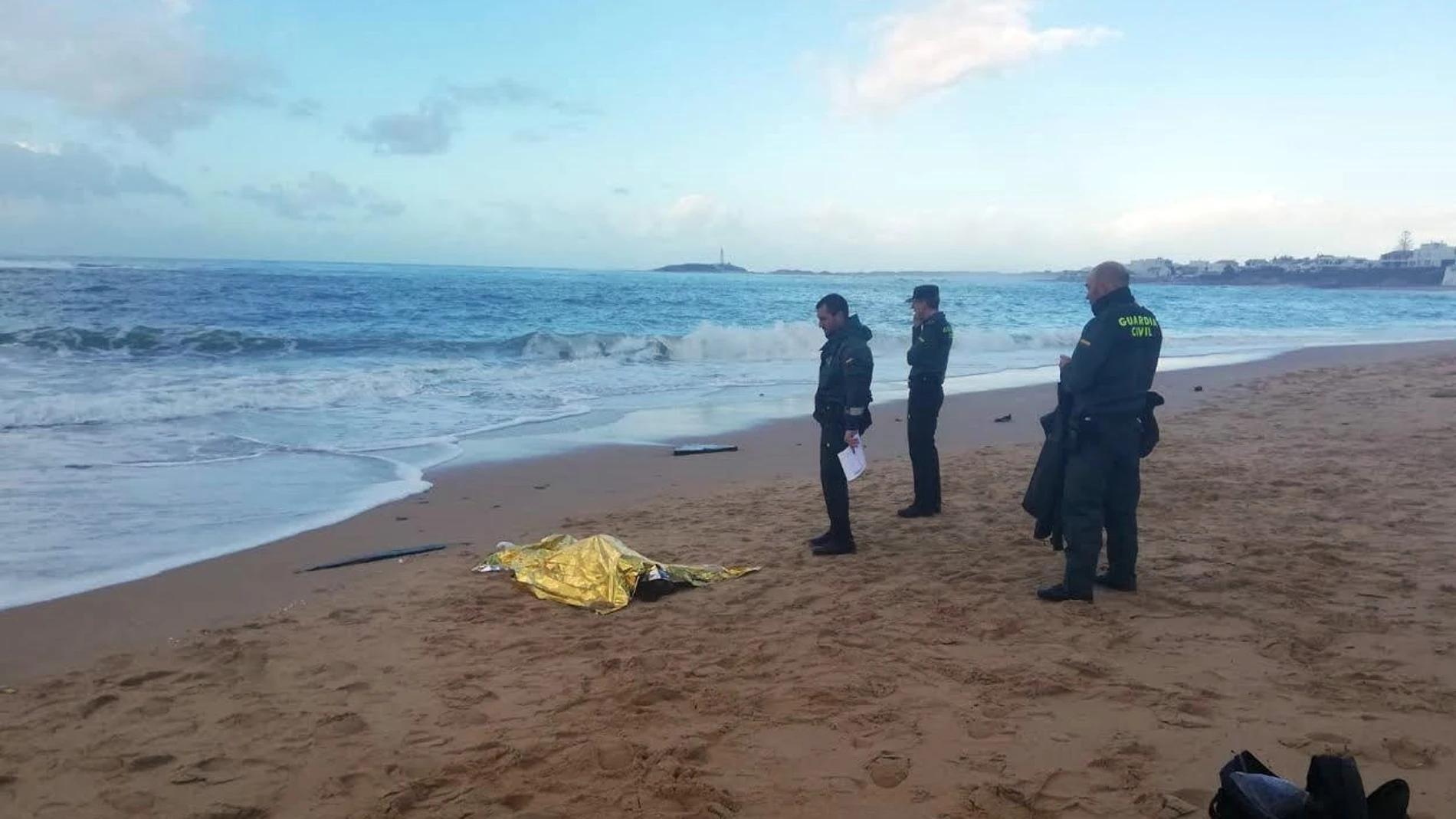 Fotografía facilitada por la Guardia Civil que muestra a agentes junto al cuerpo de uno de los inmigrantes fallecidos en la costa de Melilla