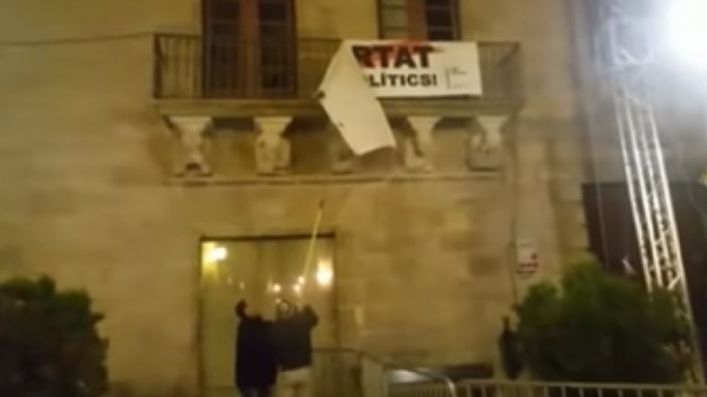 Dos personas descuelgan la pancarta por los pol&iacute;ticos presos del balc&oacute;n del Ayuntamiento de Cervera
