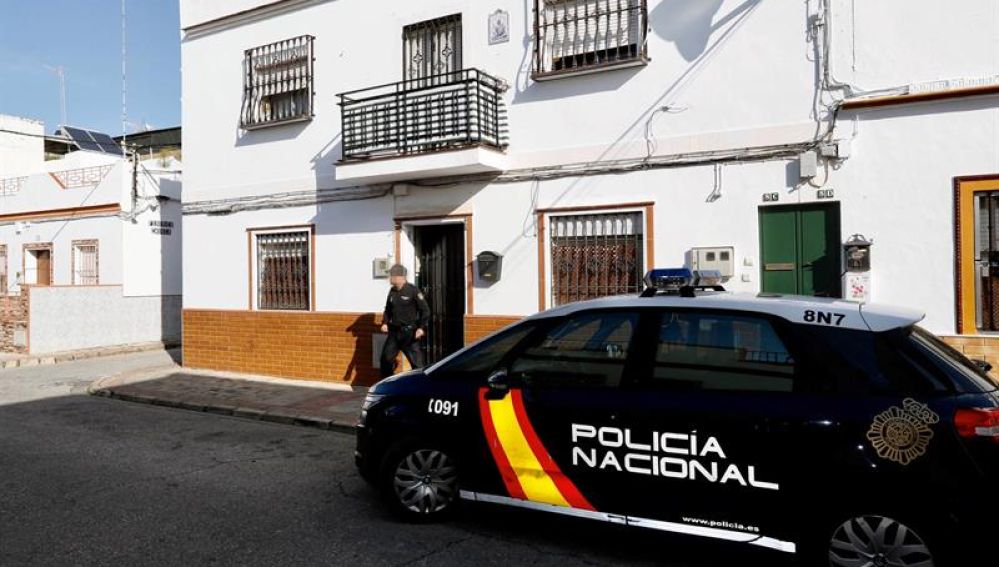 Un agente de la Policía Nacional sale de la vivienda de Alcalá de Guadaira