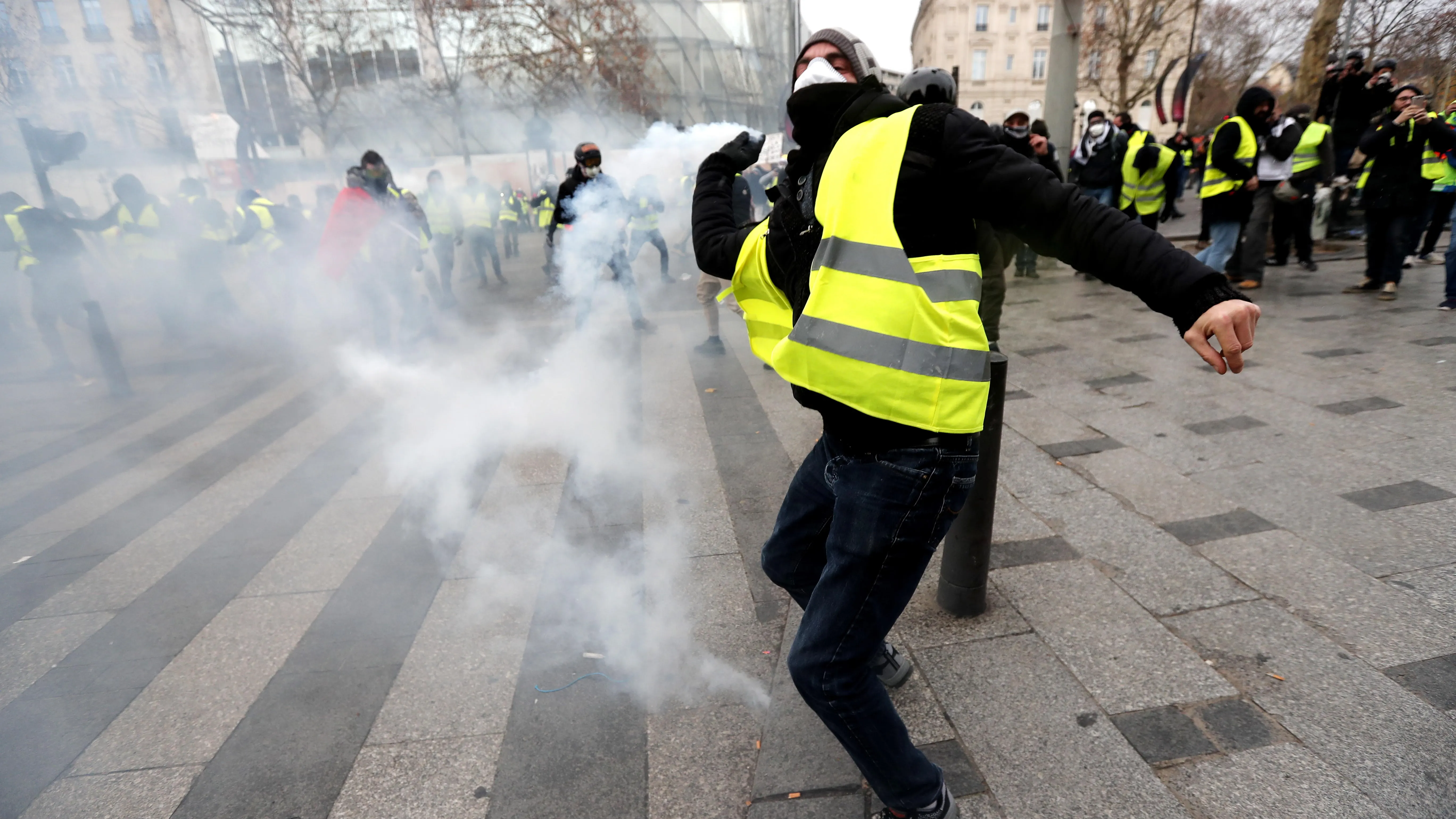 Un manifestante de los 'chalecos amarillos' lanza gas lacrimogeno