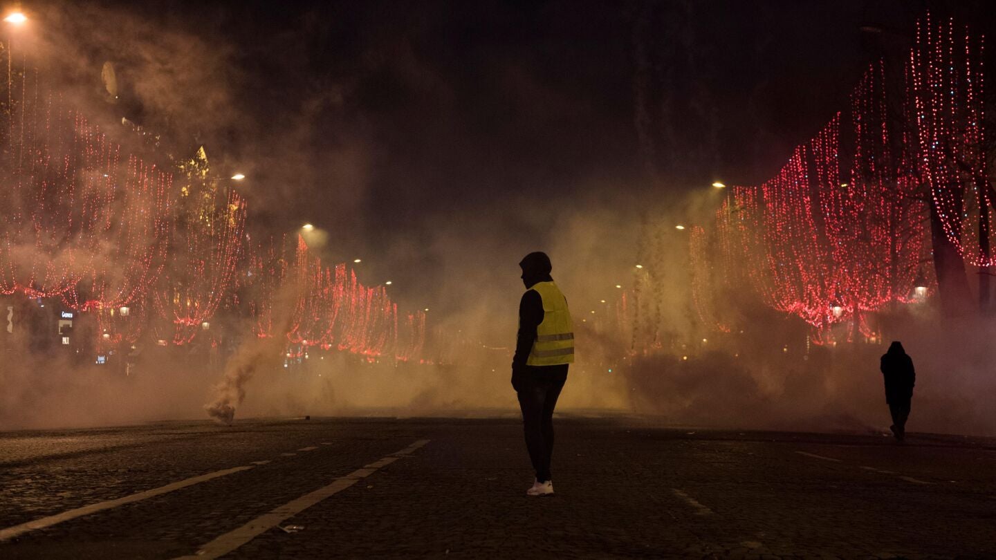 Un manifestante de chaleco amarillo est&aacute; parado en medio del humo durante una manifestaci&oacute;n en Par&iacute;s