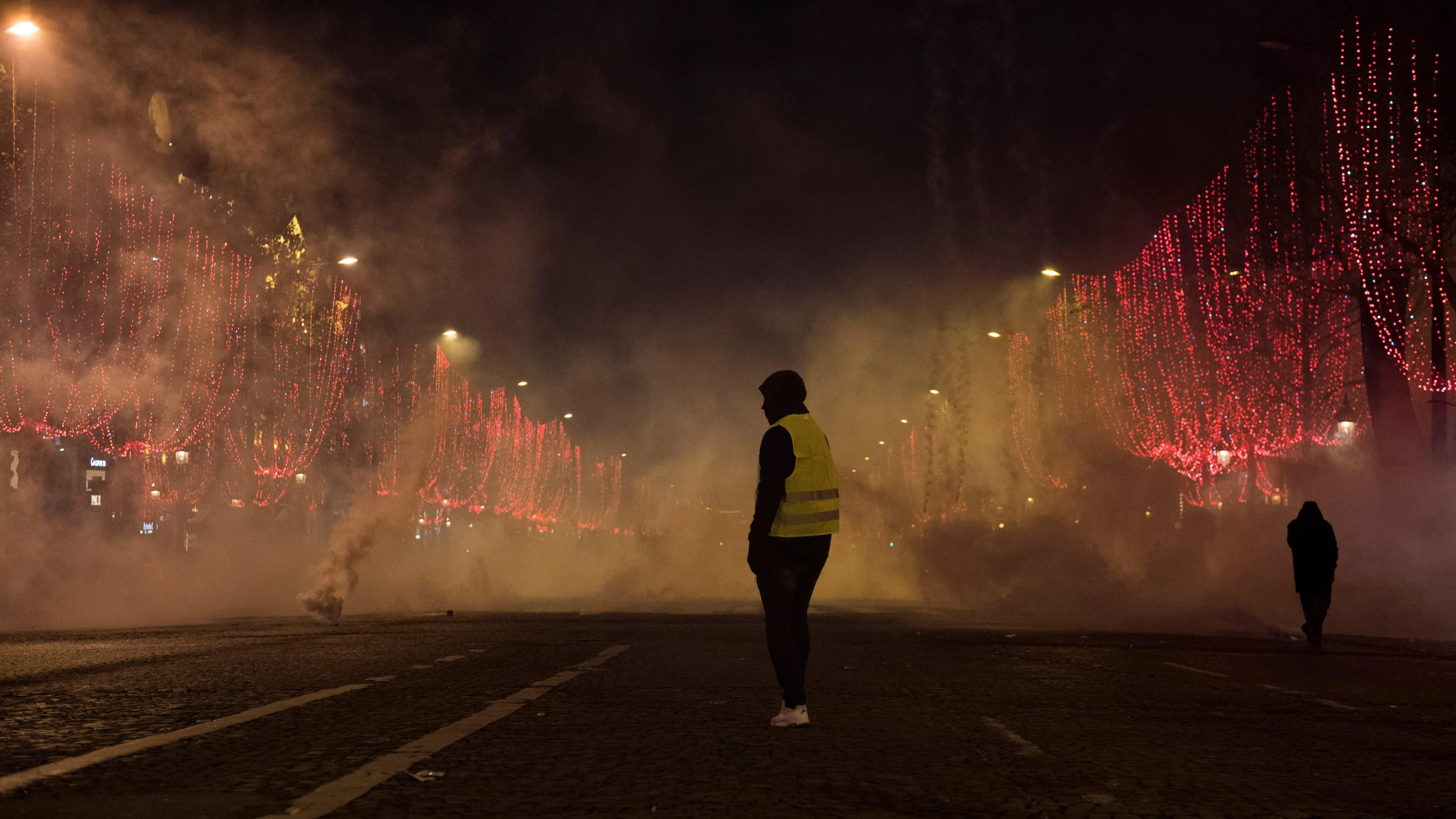 Un manifestante de chaleco amarillo está parado en medio del humo durante una manifestación en París