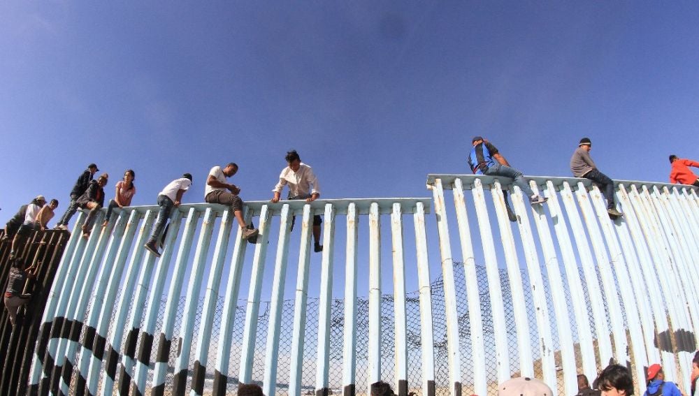Migrantes saltando la valla fronteriza de EEUU