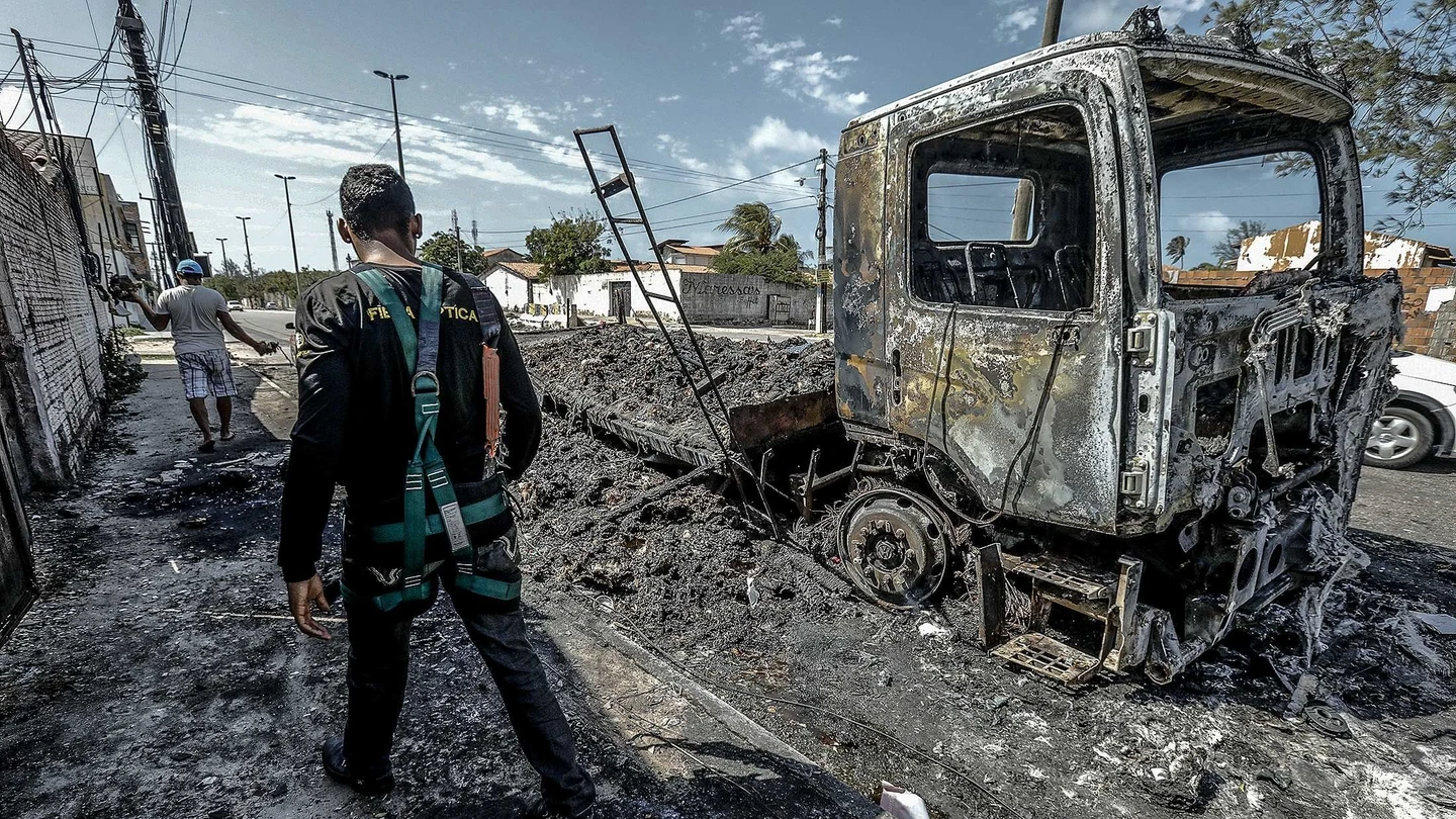 Un hombre camina frente a un vehículo quemado tras un ataque hoy, en Fortaleza (Brasil) Un hombre camina frente a un vehículo quemado tras un ataque hoy, en Fortaleza (Brasil)