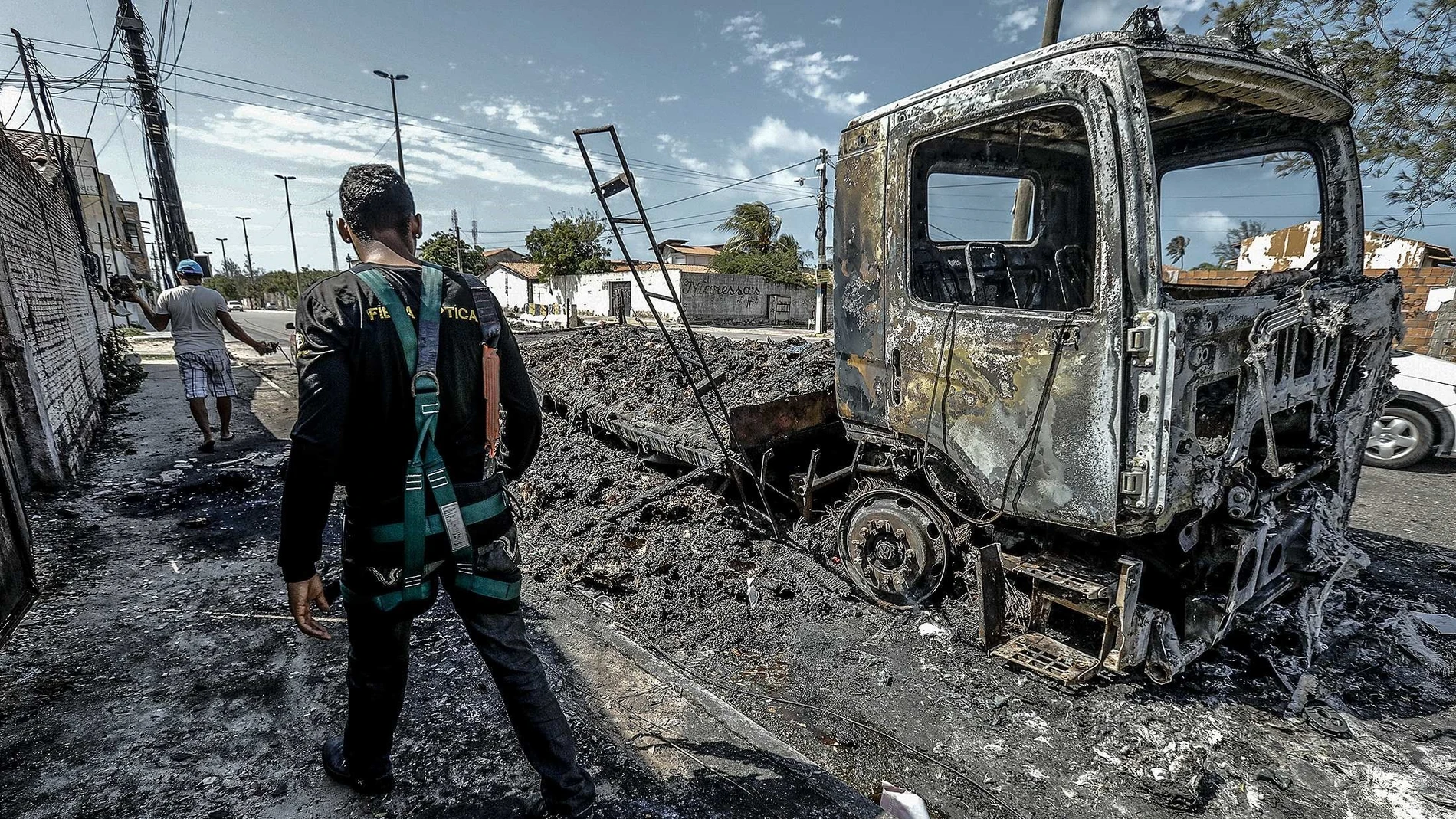 Un hombre camina frente a un vehículo quemado tras un ataque hoy, en Fortaleza (Brasil)