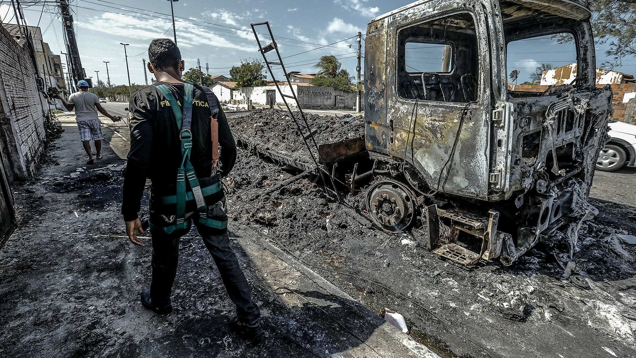 Un hombre camina frente a un vehículo quemado tras un ataque hoy, en Fortaleza (Brasil)