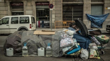Una mujer con sus pertenencias en un banco de Madrid