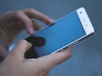 Imagen de archivo de una persona con un teléfono móvil en la mano Imagen de archivo de una persona con un teléfono móvil en la mano