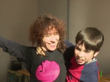 Imagen de una profesora de danza junto a un niño con autismo en una clase de danza
