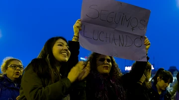 Una mujer sostiene un cartel con el lema "Seguimos luchando"