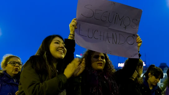 Una mujer sostiene un cartel con el lema "Seguimos luchando" Una mujer sostiene un cartel con el lema "Seguimos luchando"