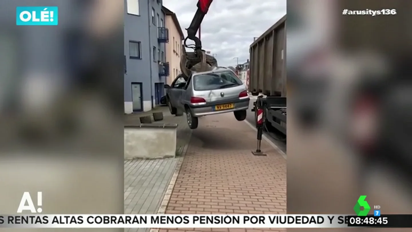 El trabajador de un desguace utiliza una de sus grúas para retirar un coche aparcado en la puerta de su garaje El trabajador de un desguace utiliza una de sus grúas para retirar un coche aparcado en la puerta de su garaje