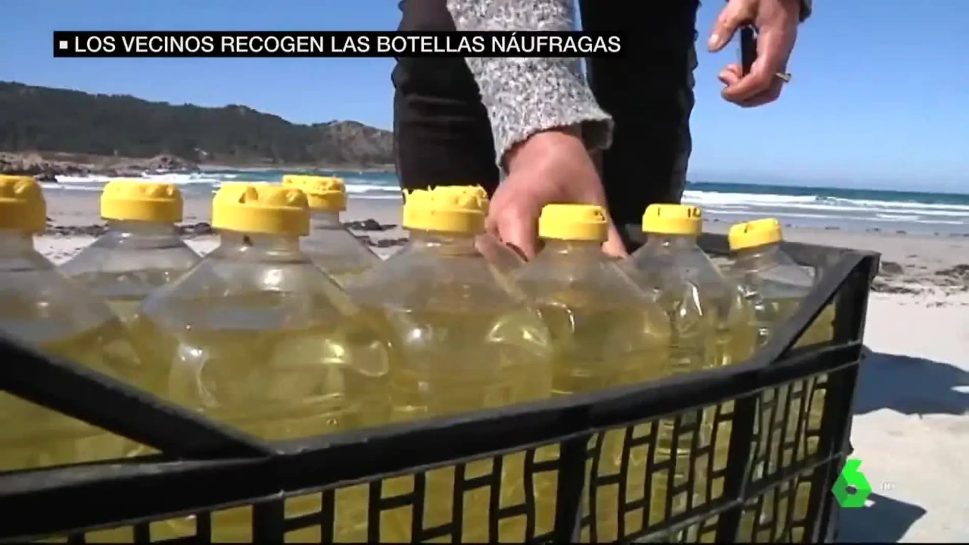 Una caja con botellas de aceite en la playa de Camariñas, A Coruña