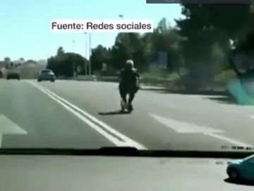Una mujer conduce un patinete por la autovía de Valencia Una mujer conduce un patinete por la autovía de Valencia