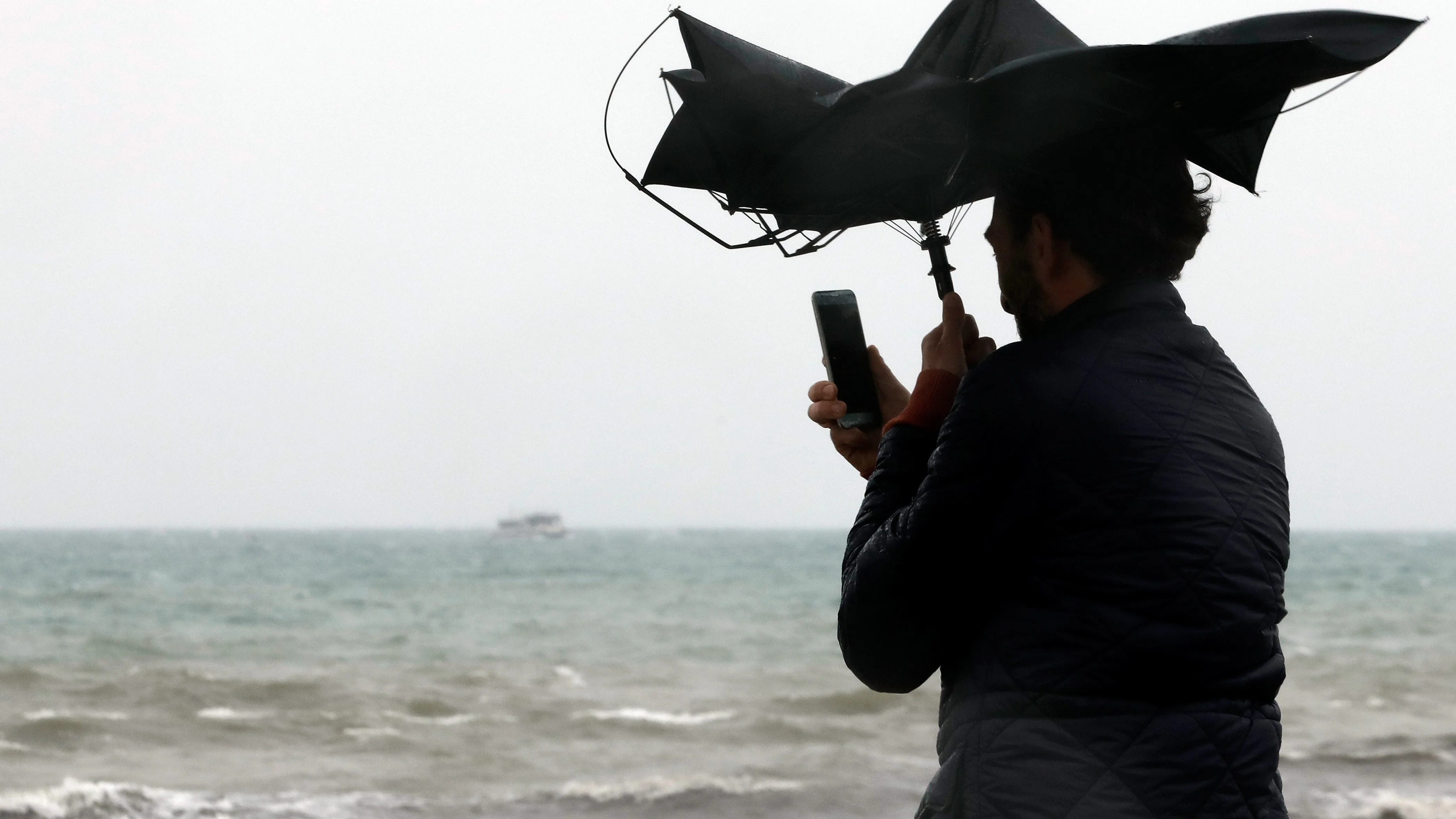 Imagen de archivo de una persona en la Playa de la Malvarrosa de Valéncia bajo la lluvia y el fuerte viento.