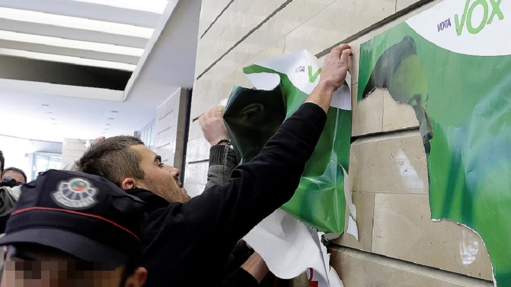 Un grupo de manifestantes quita carteles de Abascal a las puertas de un acto de Vox