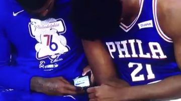 Amir Johnson y Joel Embiid miran el móvil durante el partido contra los Nets