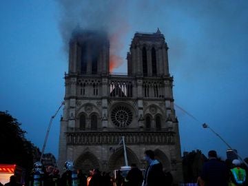 Los miembros de la brigada de bomberos de París rocían agua sobre la fachada de la catedral de Notre Dame