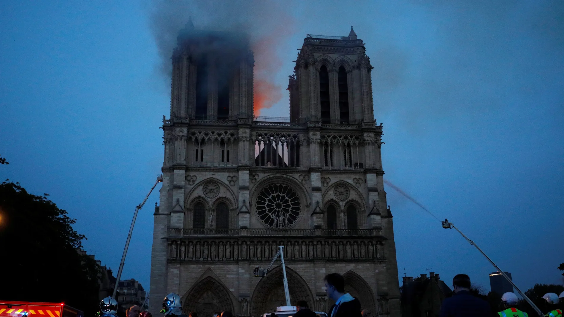 Los miembros de la brigada de bomberos de París rocían agua sobre la fachada de la catedral de Notre Dame