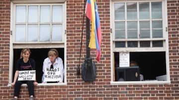 Acivistas con carteles contra Juan Guaidó en la embajada de Venezuela en Washington