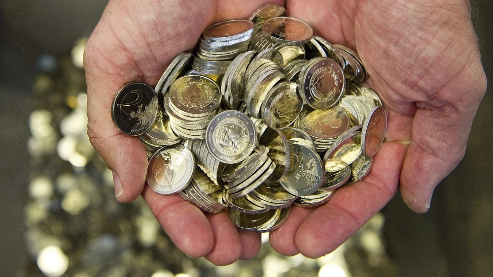 Un hombre sostiene monedas de euro