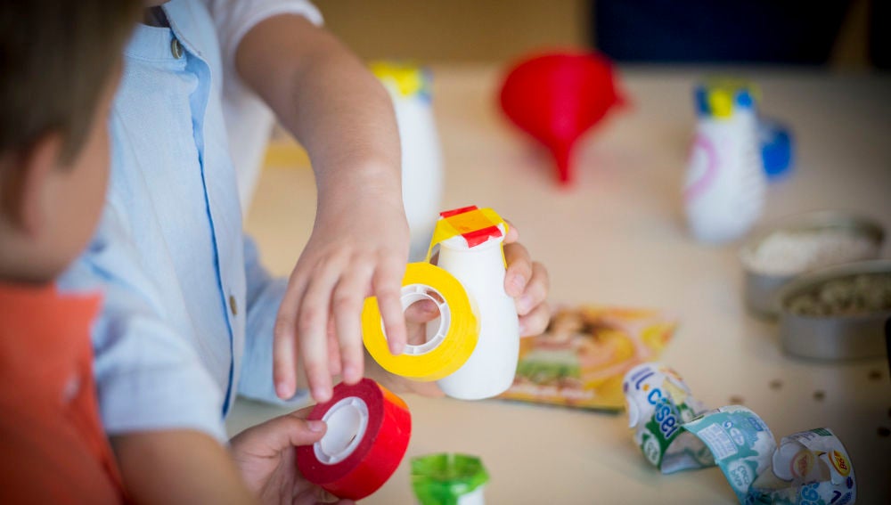 Dos niños pequeños fabrican juguetes con materiales reciclados.