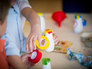 Dos niños pequeños fabrican juguetes con materiales reciclados. Dos niños pequeños fabrican juguetes con materiales reciclados.