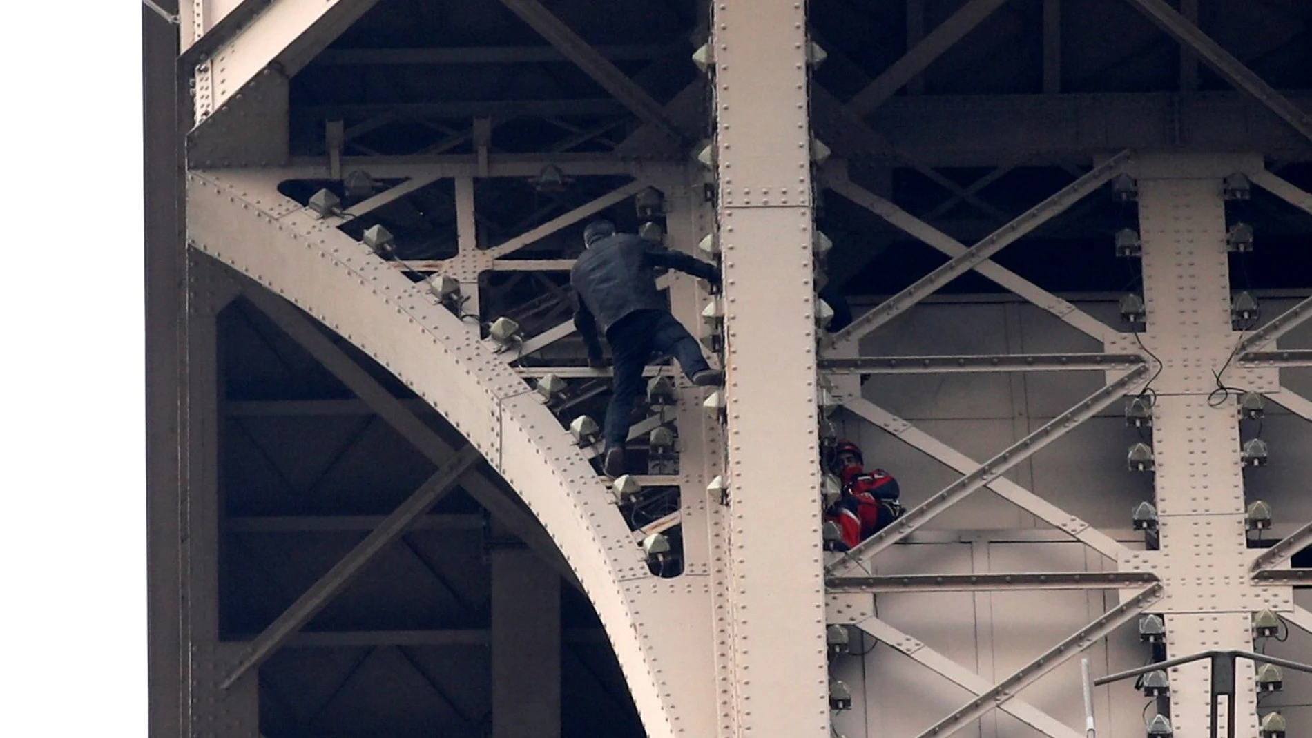 Un hombre escala la Torre Eiffel mientras varios bomberos tratan de detenerlo