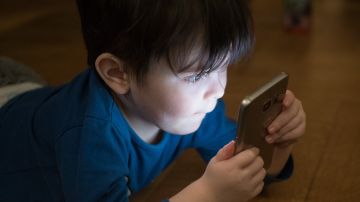 Imagen de archivo de un niño usando un teléfono móvil