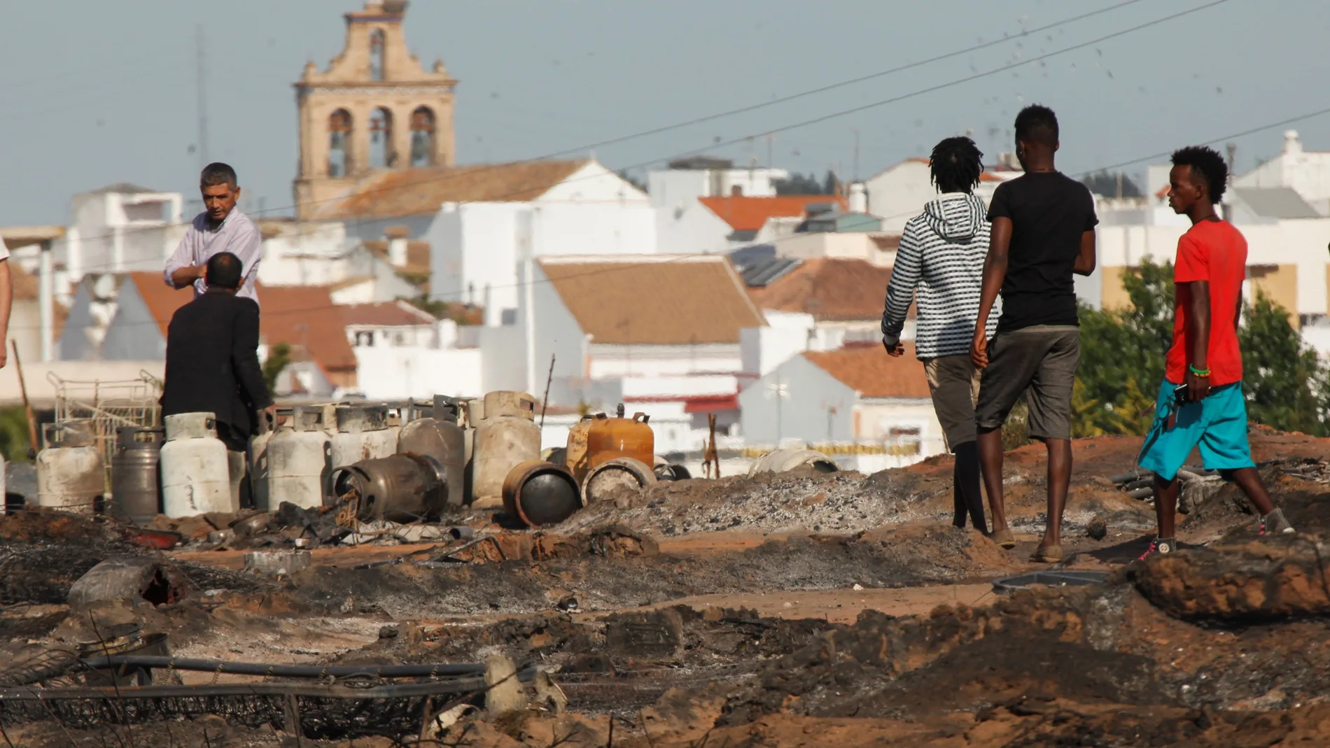 Varias personas caminan por lo que queda del asentamiento chabolista