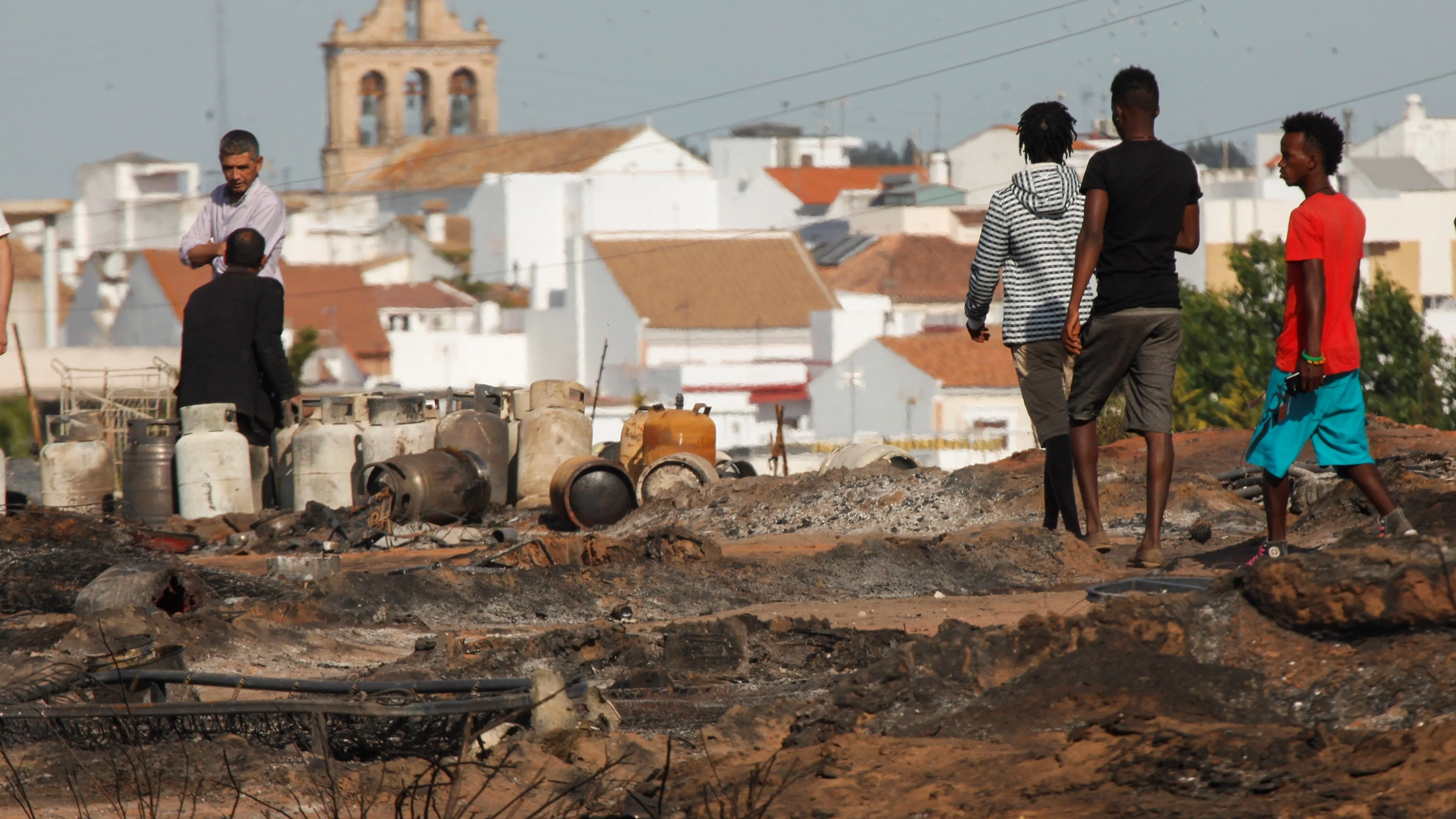 Varias personas caminan por lo que queda del asentamiento chabolista