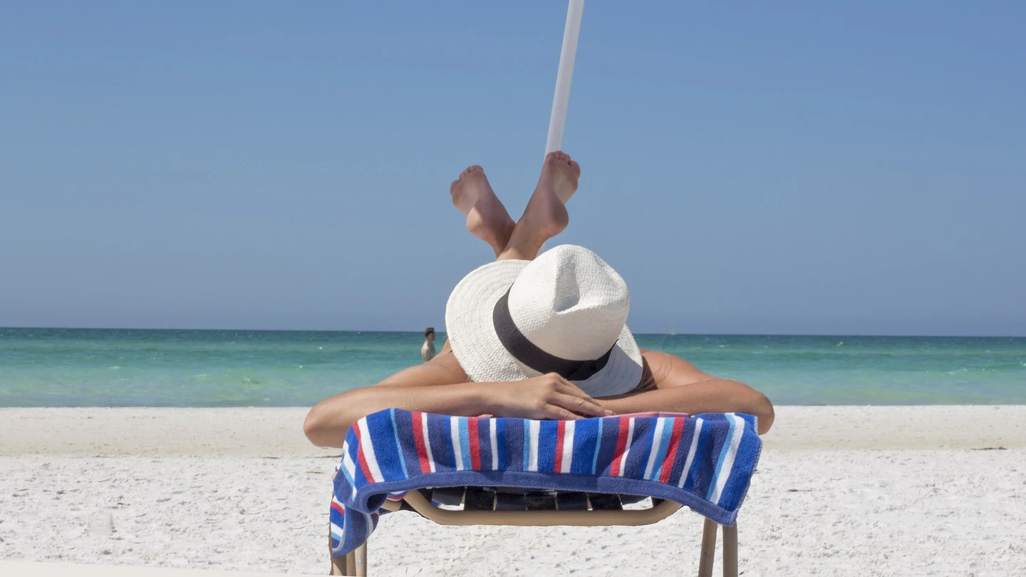 Una mujer toma el sol en una playa Una mujer toma el sol en una playa
