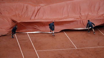 Los operarios de Roland Garros ponen la lona en la Philippe Chatrier