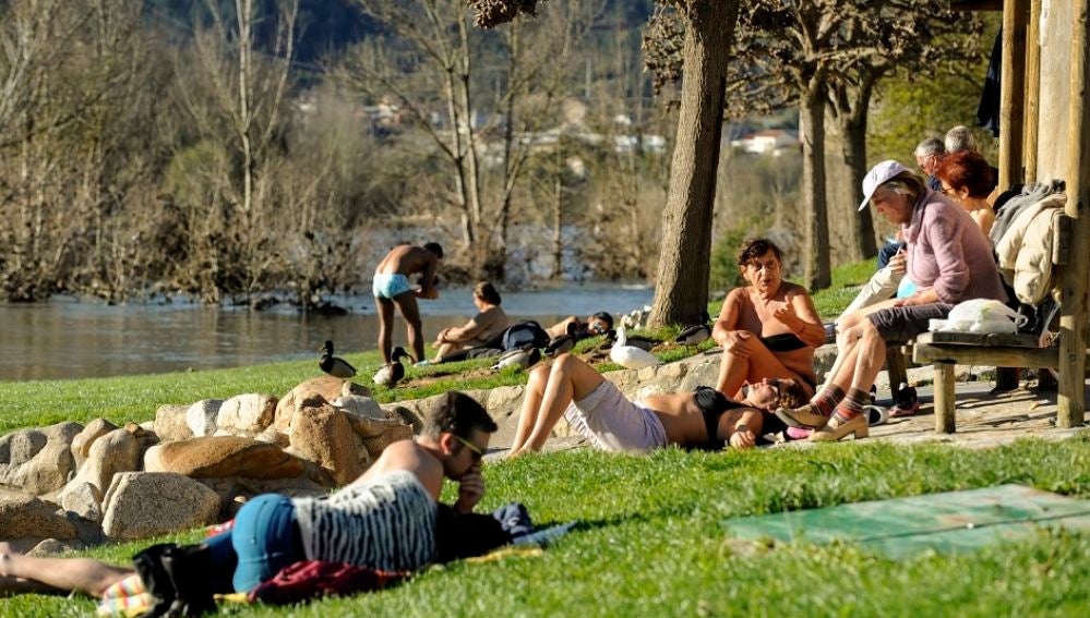 Imagen de archivo de personas tomando el sol en la zona fluvial del río Miño