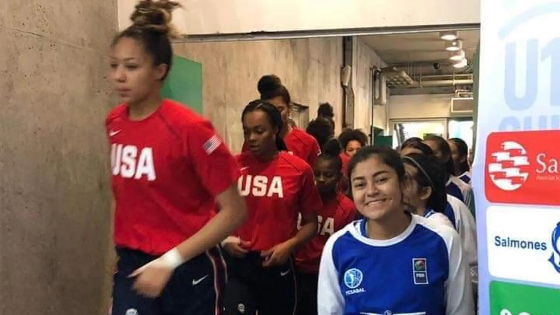 Una jugadora de El Salvador, sonriente al lado de las jugadoras estadounidenses