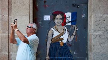 Un señor toma una fotografía junto al grafitti de 'madame Colau'