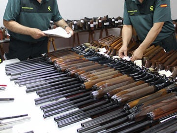 Dos agentes de la Guardia Civil revisan numerosas escopetas y armas Dos agentes de la Guardia Civil revisan numerosas escopetas y armas