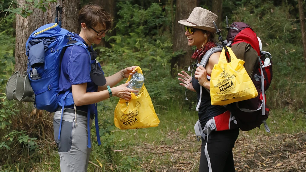 Peregrinos del Camino de Santiago separando envases para su reciclaje.