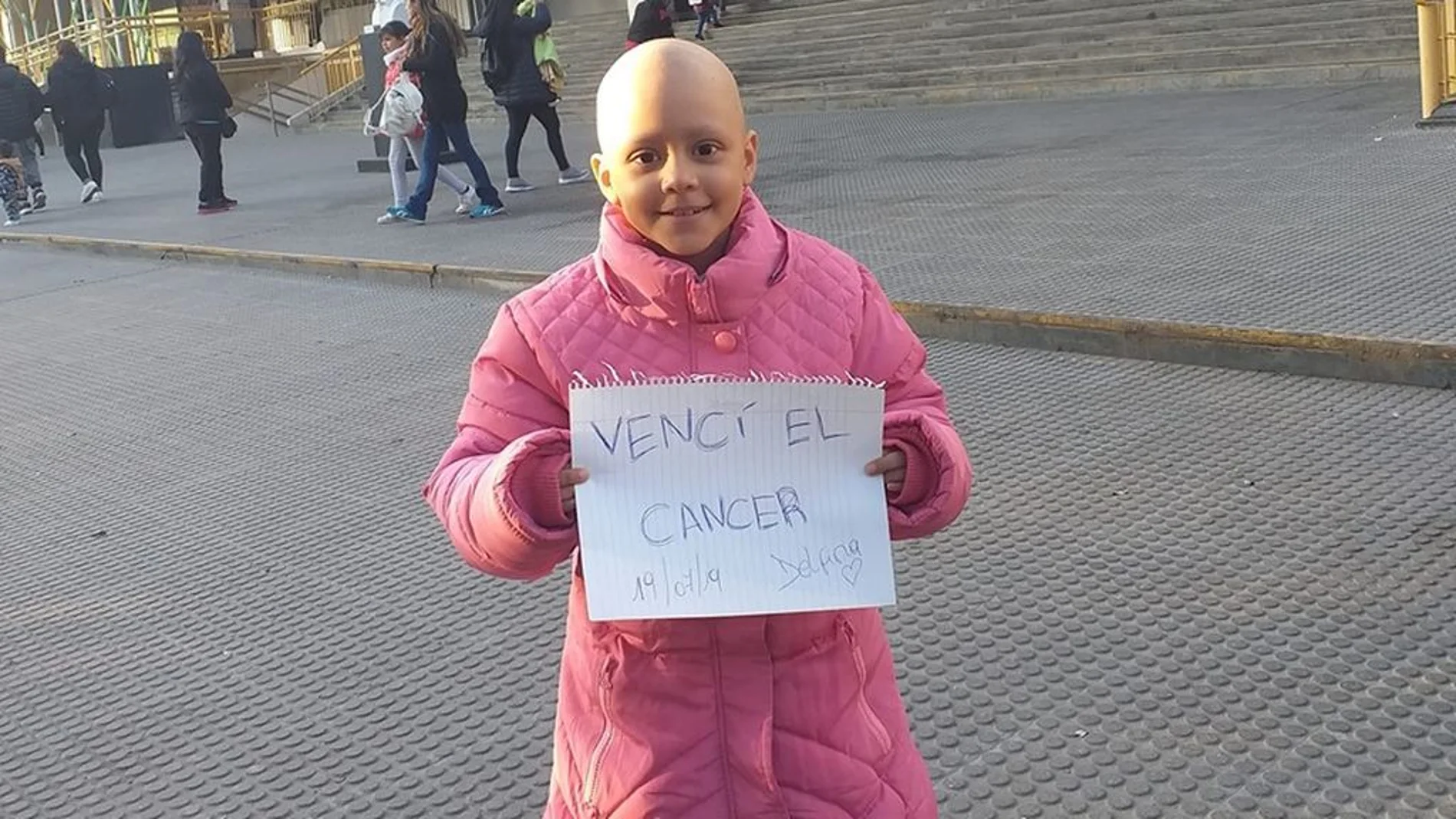 Delfina sostiene un cartel con el mensaje "vencí el cáncer"