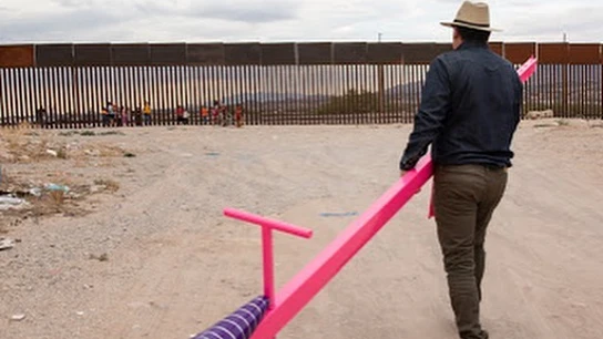 Un hombre de camino a la valla fronteriza para colocar un columpio. Un hombre de camino a la valla fronteriza para colocar un columpio.