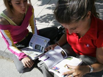 Dos jóvenes repasan el libro de conducir antes de presentarse a la prueba teórica en el centro de exámenes de la DGT